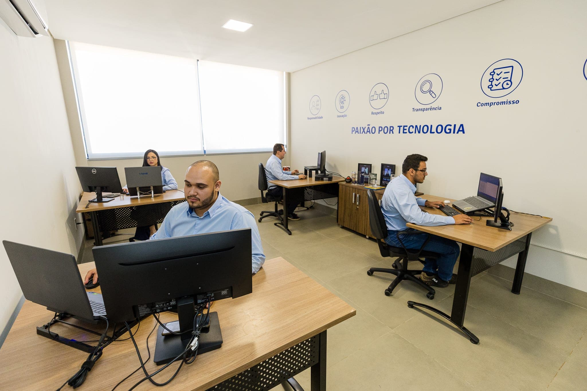 Sala de trabalho da TSMIT com a frase Paixão por tecnologia na parede