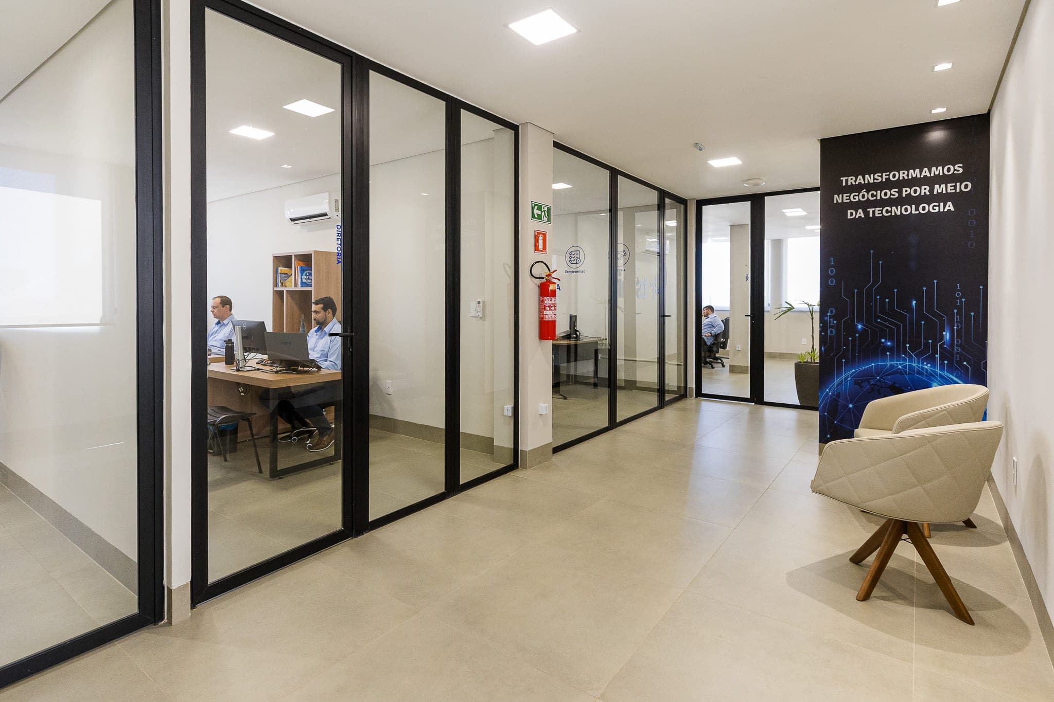 Corredor com salas de vidro na sede da TSMIT